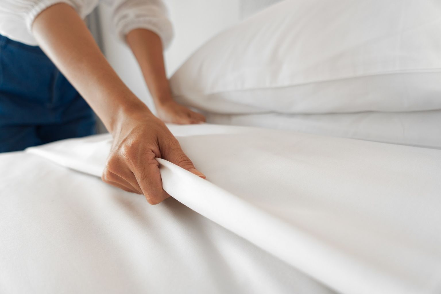 A person covers a bed. You can see only the arms and part of the bed.